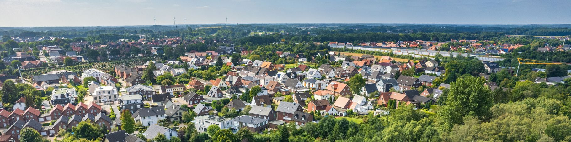 Luftansicht einer Gemeinde mit Bäumen und Häuserdächern.